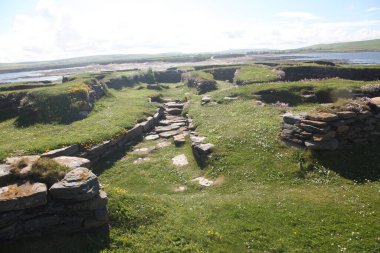 Orkney 'deki Birsay Brough kalıntıları, engebeli kayalıklara ve parlak mavi kıyı gökyüzüne karşı kurulmuş yıpranmış taş temellere sahip tarihi bir İskandinav Viking yerleşimi..