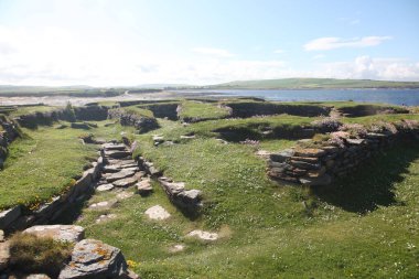 Orkney 'deki Birsay Brough kalıntıları, engebeli kayalıklara ve parlak mavi kıyı gökyüzüne karşı kurulmuş yıpranmış taş temellere sahip tarihi bir İskandinav Viking yerleşimi..