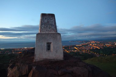 Arthurs 'un tepesindeki anıtın alacakaranlık manzarası ikonik Edinburgh tepesi, Edinburgh' a bakan şehir ve yumuşak akşam ışığında çevreleyen manzara..