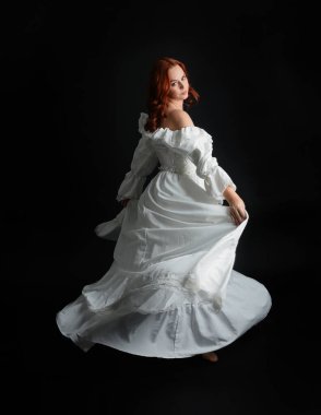 Tam boy portre güzel kadın model antika beyaz hayalet gelinlik giyiyor. Dans pozu, kameradan uzaklaşmak, arka plan. Karanlık stüdyo arka planında izole bir figür.