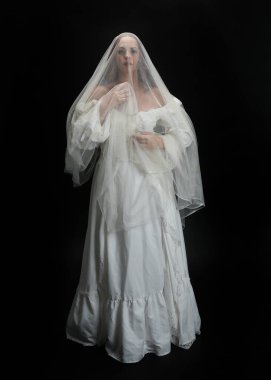 Tam boy portre güzel kadın model antika beyaz hayalet gelinlik gelinlik, ruhani duvak başörtüsü giyiyor. Karanlık stüdyo arka planında izole edilmiş bir şahsiyet.