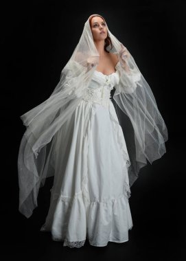 Tam boy portre güzel kadın model antika beyaz hayalet gelinlik gelinlik, ruhani duvak başörtüsü giyiyor. Karanlık stüdyo arka planında izole edilmiş bir şahsiyet.