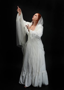 Tam boy portre güzel kadın model antika beyaz hayalet gelinlik gelinlik, ruhani duvak başörtüsü giyiyor. Karanlık stüdyo arka planında izole edilmiş bir şahsiyet.