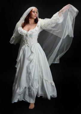 Tam boy portre güzel kadın model antika beyaz hayalet gelinlik gelinlik, ruhani duvak başörtüsü giyiyor. Karanlık stüdyo arka planında izole edilmiş bir şahsiyet.