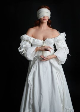 close up portrait beautiful female model wearing antique white historical ghost bride wedding dress gown, a veiled mask blindfold covering face. isolated figure on dark studio background, hands gesturing.