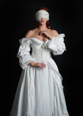 Kapalı portre güzel bayan model antika beyaz hayalet gelin gelinliği giyiyor peçeli bir maske takıyor. Karanlık stüdyo arka planında izole bir figür, el hareketleriyle.