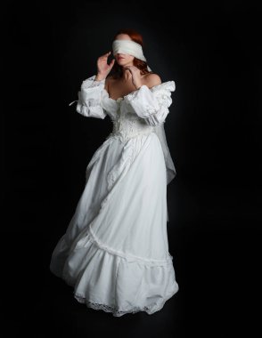 Kapalı portre güzel bayan model antika beyaz hayalet gelin gelinliği giyiyor peçeli bir maske takıyor. Karanlık stüdyo arka planında izole bir figür, el hareketi