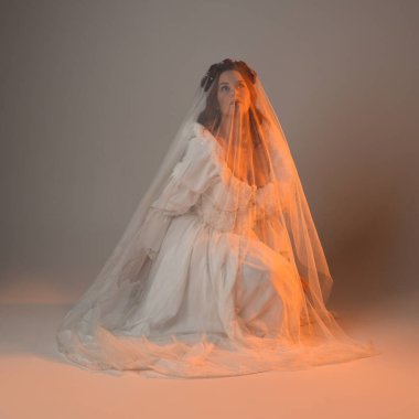 Tam boy portre, tarihi beyaz fantezi gelinlik giyen güzel kadın model, kumaş peçeli peri masalı balo elbisesi. Altın parıldayan stüdyo arka planında izole bir poz.