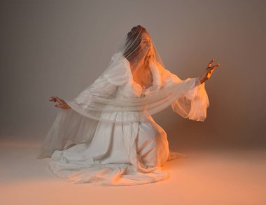 Tam boy portre, tarihi beyaz fantezi gelinlik giyen güzel kadın model, kumaş peçeli peri masalı balo elbisesi. Altın parıldayan stüdyo arka planında izole bir poz.