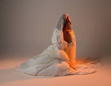 Tam boy portre, tarihi beyaz fantezi gelinlik giyen güzel kadın model, kumaş peçeli peri masalı balo elbisesi. Altın parıldayan stüdyo arka planında izole bir poz.