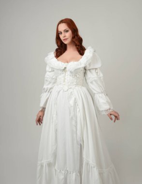 Yakın plan güzel kızıl saçlı manken tarihi fantezi gelinlik giyiyor, peri masalı balosu elbisesi giyiyor. Beyaz stüdyo arka planında izole bir figür