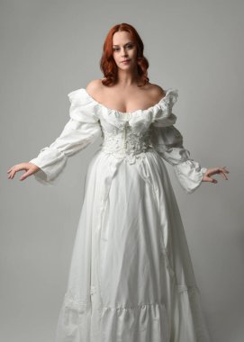 Yakın plan güzel kızıl saçlı manken tarihi fantezi gelinlik giyiyor, peri masalı balosu elbisesi giyiyor. Beyaz stüdyo arka planında izole bir figür