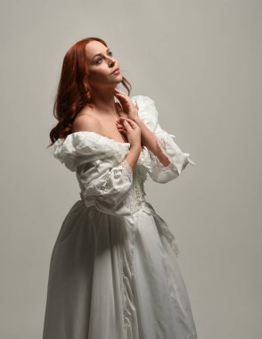 Tarihi fantezi gelinlik giyen, peri masalı balosu elbisesi giyen güzel bir kadın manken. Beyaz stüdyo arka planında yukarıdaki ışığa uzanan yalıtılmış el hareketi