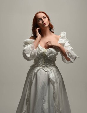 Tarihi fantezi gelinlik giyen, peri masalı balosu elbisesi giyen güzel bir kadın manken. Beyaz stüdyo arka planında yukarıdaki ışığa uzanan yalıtılmış el hareketi