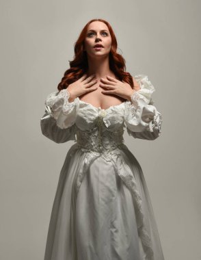 Tarihi fantezi gelinlik giyen, peri masalı balosu elbisesi giyen güzel bir kadın manken. Beyaz stüdyo arka planında yukarıdaki ışığa uzanan yalıtılmış el hareketi