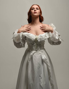 Tarihi fantezi gelinlik giyen, peri masalı balosu elbisesi giyen güzel bir kadın manken. Beyaz stüdyo arka planında yukarıdaki ışığa uzanan yalıtılmış el hareketi