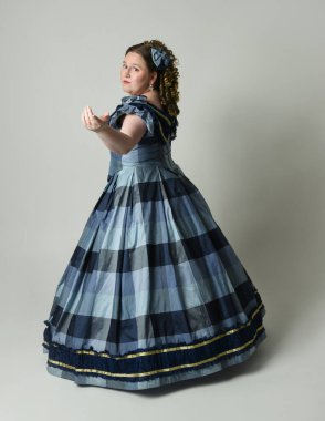 Viktorya Dönemi 'nden kalma klasik Mavi Balo Elbisesi, artı boyut modeli, tam boy Arka Görünüm pozu giymiş Viktorya dönemi kadını uzaklaşıyor. Stüdyo arkaplanındaki izole kişi.