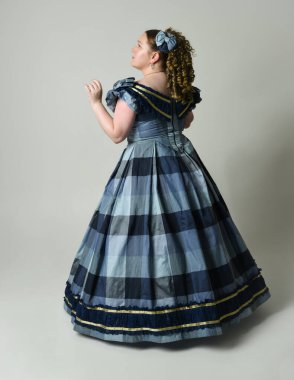 Viktorya Dönemi 'nden kalma klasik Mavi Balo Elbisesi, artı boyut modeli, tam boy Arka Görünüm pozu giymiş Viktorya dönemi kadını uzaklaşıyor. Stüdyo arkaplanındaki izole kişi.