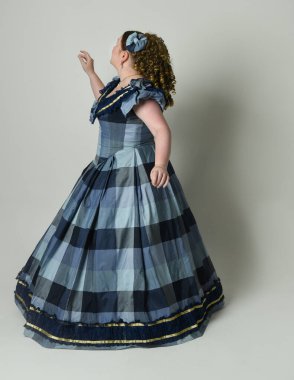 Viktorya Dönemi 'nden kalma klasik Mavi Balo Elbisesi, artı boyut modeli, tam boy Arka Görünüm pozu giymiş Viktorya dönemi kadını uzaklaşıyor. Stüdyo arkaplanındaki izole kişi.