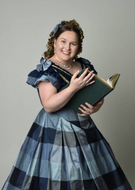 Viktorya Dönemi kadınının tarihi klasik Mavi Balo elbisesi içinde portresi artı boyut modeli elinde bir kitap tutuyor. Stüdyo arkaplanındaki izole kişi.