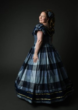 Viktorya dönemi kadınının tarihi klasik mavi balo elbisesi içinde tam boy portresi, güzel artı beden modeli. İzole edilmiş siluet figürü, uzaklaşıyor, arka plan, karanlık stüdyo arka plan..