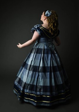 Viktorya dönemi kadınının tarihi klasik mavi balo elbisesi içinde tam boy portresi, güzel artı beden modeli. İzole edilmiş siluet figürü, uzaklaşıyor, arka plan, karanlık stüdyo arka plan..