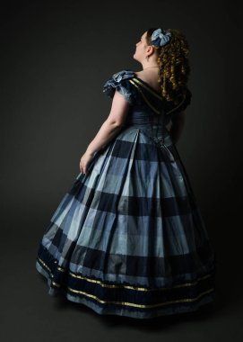 Viktorya dönemi kadınının tarihi klasik mavi balo elbisesi içinde tam boy portresi, güzel artı beden modeli. İzole edilmiş siluet figürü, uzaklaşıyor, arka plan, karanlık stüdyo arka plan..