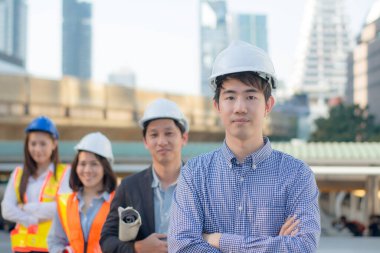 Portre mutlu takımı, Asyalı işadamı ve iş kadını bir grup profesyonel mühendis ve mimar şantiyede çalışıyor, bina planlarıyla, iş yerinde, üç ortakla birlikte.