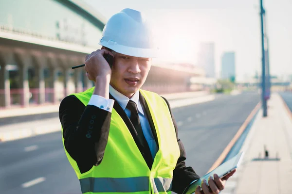 Asian manager engineer with hardhat,work outside industry,use digital tablet,radio communication control,with walkie talkie,work survey building construction factory site,business working and industry