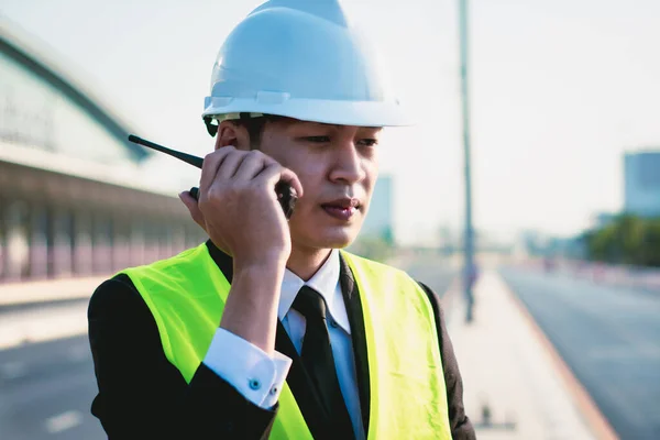 Asian manager engineer with hardhat,work outside industry,use digital tablet,radio communication control,with walkie talkie,work survey building construction factory site,business working and industry