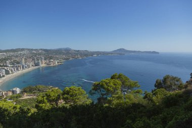 Akdeniz manzaralı dağ manzarası, mavi gökyüzü, yeşil ağaçlar ve güneşli yaz gününde İspanya 'nın Calpe kayası..