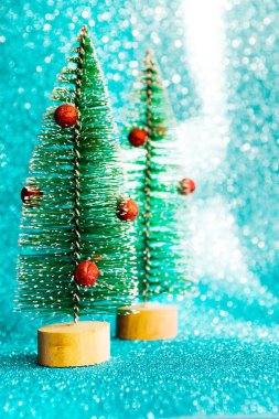 İki küçük Noel dekoratif köknar ağacı mavi parlak arka planda. Şenlikli Noel arkaplanı.