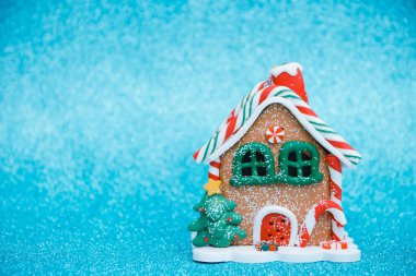 Noel oyuncağı zencefilli kurabiye şeklinde, arka planı mavi, parlak ve kopyalanmış bir ev. Seçici odak.