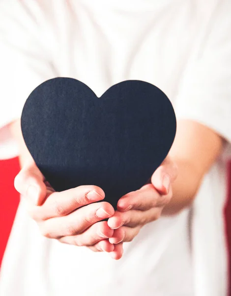 black heart shape in human hand, valentine\'s day. Selective focus.