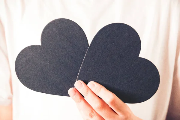 two black hearts shape in hands, valentine\'s day, heart shape, positive emotion. Selective focus.