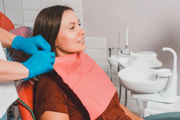 A young woman is preparing for a dental examination by a dentist, the patient is sitting in a dental chair. Happy patient in a dental chair 2020
