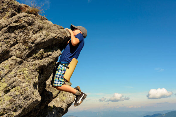 The boy is engaged in mountaineering, a child climbing a rocky mountain, a brave boy.