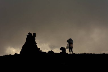 Brebeneskul Dağı 'nın tepesindeki bulutlarda iki turist, yağmurlukların üstünde duran turistler, kasvetli hava. 2020