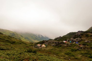 Turistler dağlardaki yağmurdan sonra sisi göl kenarındaki çadır kampını, çadırlardaki turistleri izliyor. 2020