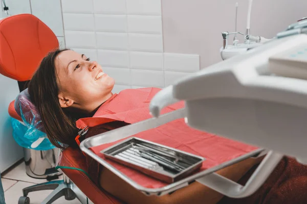 A young woman is preparing for a dental examination by a dentist, the patient is sitting in a dental chair. Happy patient in a dental chair 2021.