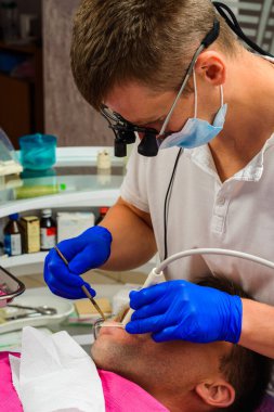 Diş hekimliği, özel muayenehane, dişçi en iyi sonuç ve çalışma için dürbün kullanır, tarı çıkarma süreci. 2020