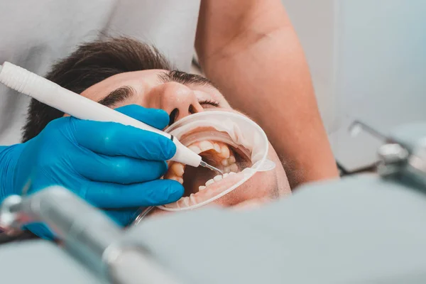 Dental practice, the dentist removes stones and hard plaque from the teeth with the help of ultrasound,patient with retractor and saliva ejector in the mouth.2020