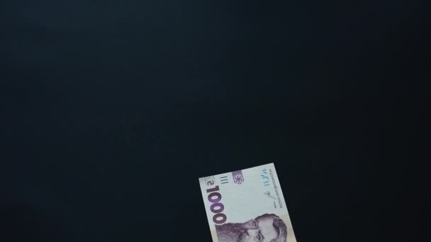 Banconote del valore nominale di mille grivne, mosche di denaro, cadute su una superficie nera, nuovi tagli di grivna. — Video Stock