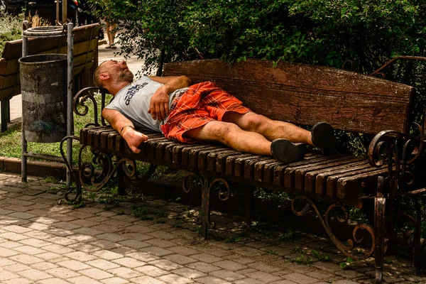 2020年7月28日 ホームレスの男性が夏にベンチの公園で寝る 2020年 — ストック写真