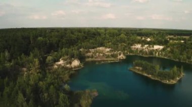 Ukrayna 'daki bazalt sütunların ve gök mavisi göllerin muhteşem manzarası. Hızlanan bir adamın insansız hava aracını sürerken dinamik videosu güzel bir manzaranın arka planında bir kayanın üzerinde oturuyor..