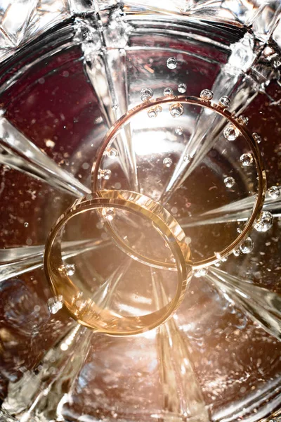 水のグラスの底にブライダルリング泡と光の輝き2020 — ストック写真
