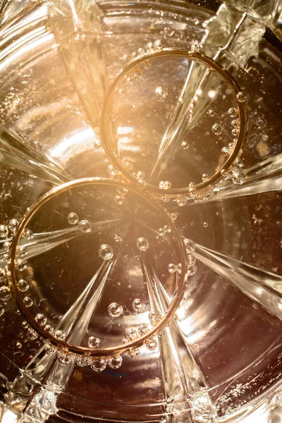 水のグラスの底にブライダルリング泡と光の輝き2020 — ストック写真