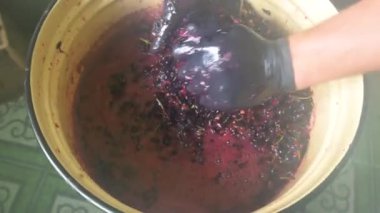 Siyah eldivenli çiftçi bir sürü üzümü ezer. El yapımı şarap yapma zanaatı..