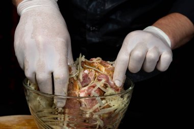 Adam domuzu marine ediyor, rendelenmiş patatesleri ekliyor ve lezzetli ve sulu bir kebap hazırlıyor.