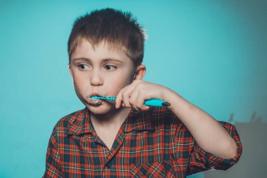 Diş fırçalayan yakışıklı çocuk, günlük prosedür, pijamalı bebek, diş bakımı. Tiksinerek dişlerini fırçalayan ve diş macununu buruşturan bir çocuk..